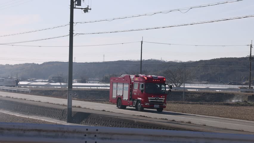 Kobe, Japan - February 5, 2023: Fire truck with flashing lights on rural road turns at intersection