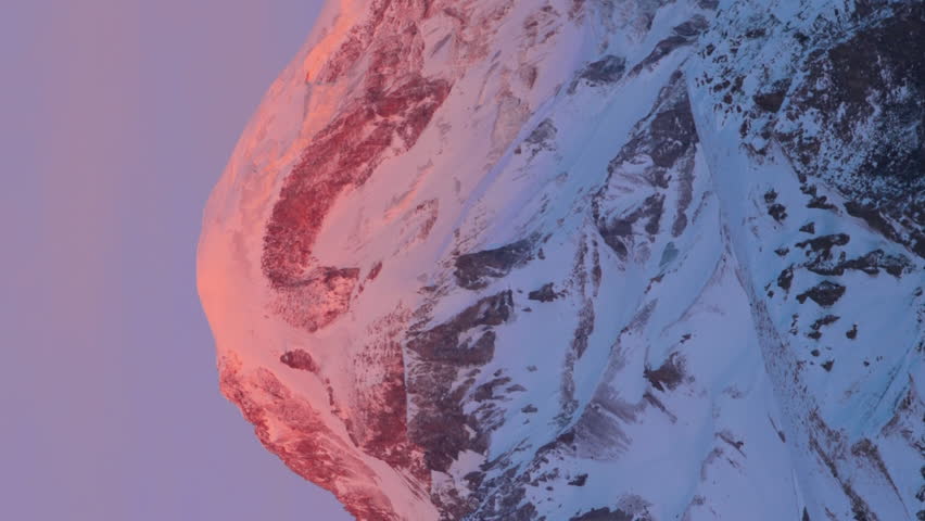 Stepantsminda, Gergeti, Georgia. Mount Kazbek Covered Snow In Winter Sunrise. Morning Dawn Colored Top Of Mountain In Pink-orange Colors. Awesome Winter Georgian Nature Landscape. Vertical Footage.