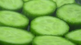 A macro close up shot, falling salt grains on a cut slices of a fresh green cucumber, slow motion 4K video