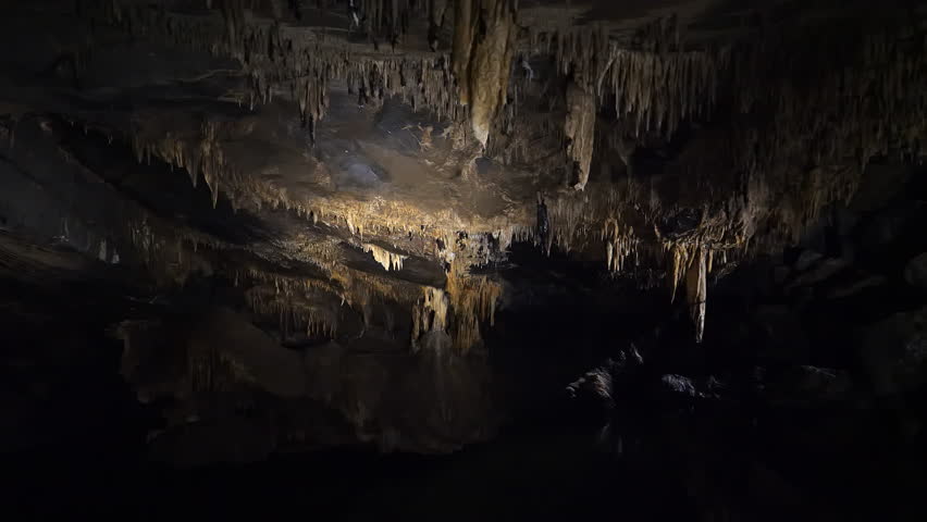 Dark Cave with Stalactites Hanging from the Ceiling.