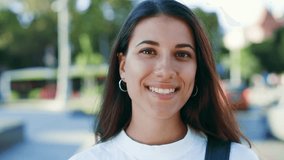 Portrait of a beautiful dark haired hispanic woman smiling look at camera standing in the urban city centre background at sunny warm weather wearing casual white t-shirt. Happy Young Woman Enjoys Life - Powered by Shutterstock - Get 15% off with code: PIKWIZARD15
