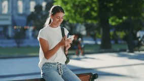 Beautiful hispanic latin sitting at branch in city square  using smartphone at sunny weather park threes background. Smiling beautiful female using mobile phone. - Powered by Shutterstock - Get 15% off with code: PIKWIZARD15