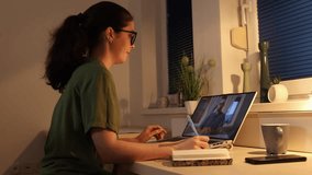 Videocall. Side view of young Caucasian woman works at laptop. Remote work and freelancing