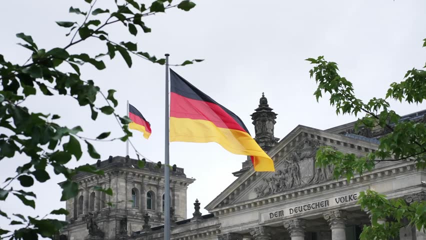 German flag on top of Reichstag building, seat of the German Parliament. National landmark in Berlin, historic building in Germany.