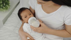 mother feeding milk bottle to her newborn baby on a bed - Powered by Shutterstock - Get 15% off with code: PIKWIZARD15