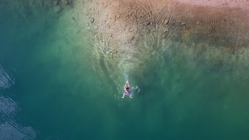 Aerial ascends from woman swimming in ice cold mountain Lake Louise Royalty-Free Stock Footage #1099927303