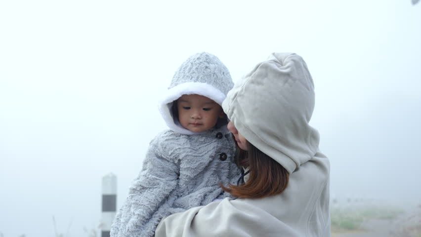 4K, young woman wearing a hooded long sleeve with hat sister, held sister in arms due current weather, alleviate my sister cold, adorable little sister smiled sweetly, Both them were in middle fog.