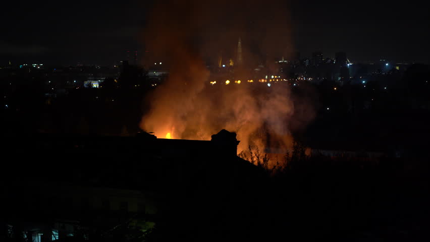 Building on fire at night in city. Orange flames and heavy smoke pouring out of burning damaged house during nighttime. Fire hazard in buildings concept