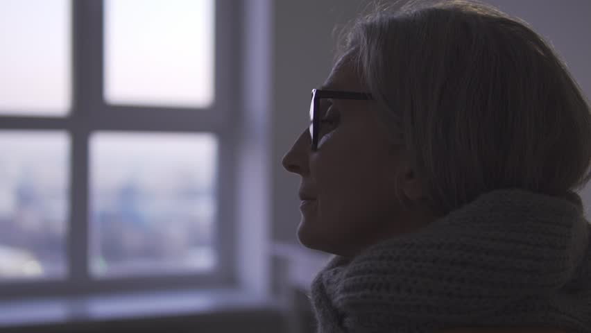 Upset sick woman sitting in her room and looking at window, nursing home living | Shutterstock HD Video #1099935225
