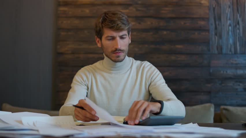Portrait of a young financier working with documents, focused accountant working overtime, calculates expenses, the thinking process. | Shutterstock HD Video #1099936087
