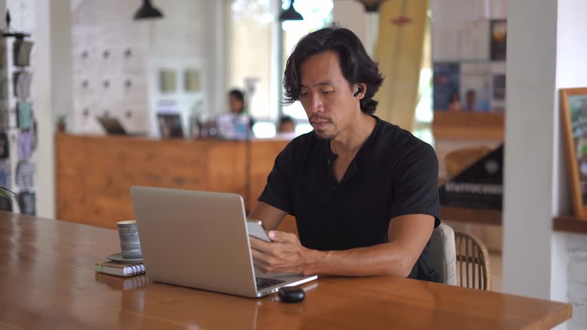 Asian freelancer online sit work job cafe. Busy people talk video link conference. Boss person use cell mobile phone meeting call covid-19. Guy user iphon chat Asia. Man start up airpoding headphones.