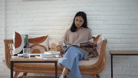 Chinese young adult woman sit rest cafe flip fashion magazine. Asian girl read catalogue. Korean female turn log page. Japanese people view news paper. Thai lady relax cozy sofa. Person look journal. - Powered by Shutterstock - Get 15% off with code: PIKWIZARD15