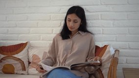 Chinese young adult woman sit rest home flip fashion magazine. Asian girl read catalogue. Korean female turn log page. Japanese people view news paper. Thai lady relax cozy sofa. Person look journal. - Powered by Shutterstock - Get 15% off with code: PIKWIZARD15
