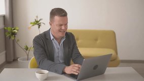 a man with a cheerful face in a jacket works on a laptop. Full HD video recording. Slow motion video