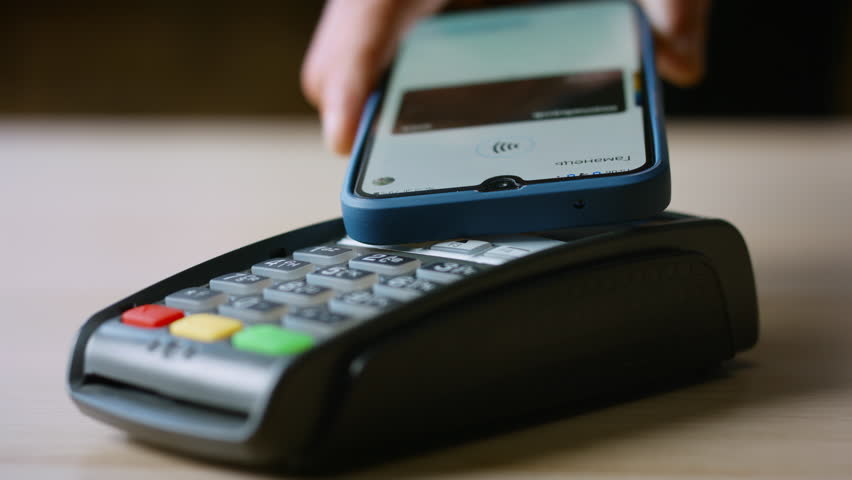 Man hand using nfc technology on cellphone for cashless purchase closeup. Unknown person making contactless payment touching pos terminal card reader with smartphone. Electronic money pay pass concept | Shutterstock HD Video #1099944295