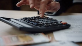 Unknown man using calculator counting corporate budget indoors close up. Male hands pressing calculator buttons analyzing business income. Accountant working at table with documents bills money cash. - Powered by Shutterstock - Get 15% off with code: PIKWIZARD15