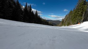 Skiing. Action camera low angle view of skis of skier going downhill on alpine ski on snow slopes in the mountains. Man going downhill on ski having fun on slopes. Winter sport outdoor activity video
