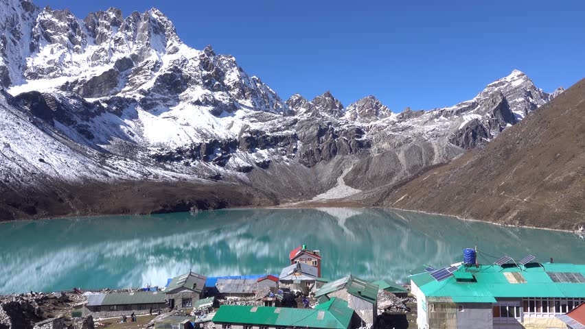 turquoise Gokyo lake with reflection of Himalayan snow covered mountains
 Gokyo village colorful huts and clear blue sky, himalaya, Everest National Park, Nepal, 2023,slow motion

