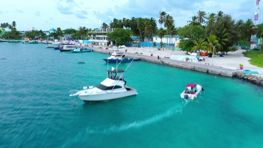 Aerial Forward Scenic View Of Houses On Island Amidst Sea, Drone Ascending Over Trees Under Clouds - Thulusdhoo, Maldives