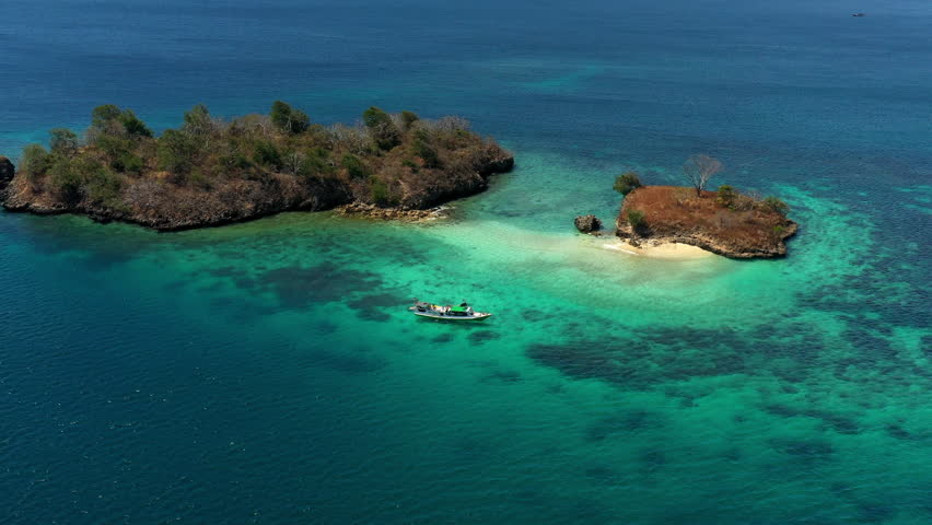 Aerial Panning Shot Of Nautical Vessel Floating On Sea By Islands, Drone Flying During Sunny Day - Lombok, Indonesia