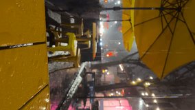 Raindrops fall on the bright yellow table and umbrella of the street cafe. Wet furniture. Vertical video orientation. Late evening. Heavy raining in New York, USA, autumn weather.