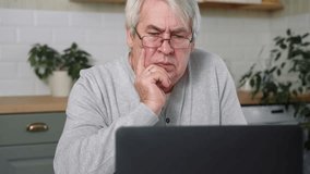 Old man Thinking at Laptop. Pensive Mature Grey hair 60s - 70s Aged Man Sitting at Table with laptop. Thoughtful retired Senior male works online at computer from home, Solving Problems with Solutions - Powered by Shutterstock - Get 15% off with code: PIKWIZARD15