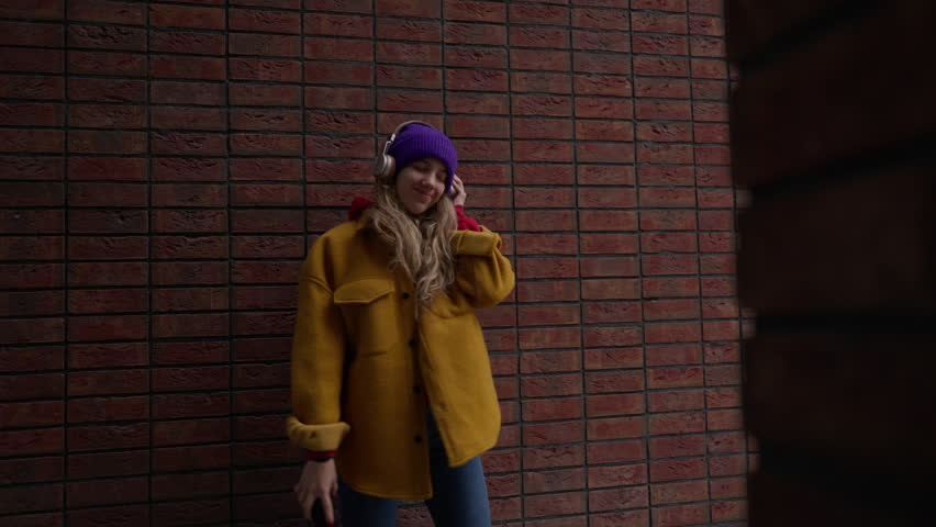 Young woman listening music outdoor, in a city.