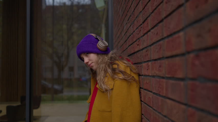 Young woman listening music outdoor, in a city.