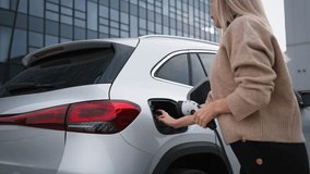 Close-up of young woman charging her electric car. - Powered by Shutterstock - Get 15% off with code: PIKWIZARD15