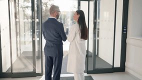 Rear view of businessman talking and explaining something to young woman doctor. - Powered by Shutterstock - Get 15% off with code: PIKWIZARD15