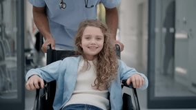 Young caregiver pushing little girl on wheelchair at hospital corridor, having fun together. - Powered by Shutterstock - Get 15% off with code: PIKWIZARD15