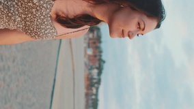 VERTICAL VIDEO: Young woman walking along the beach in the early morning