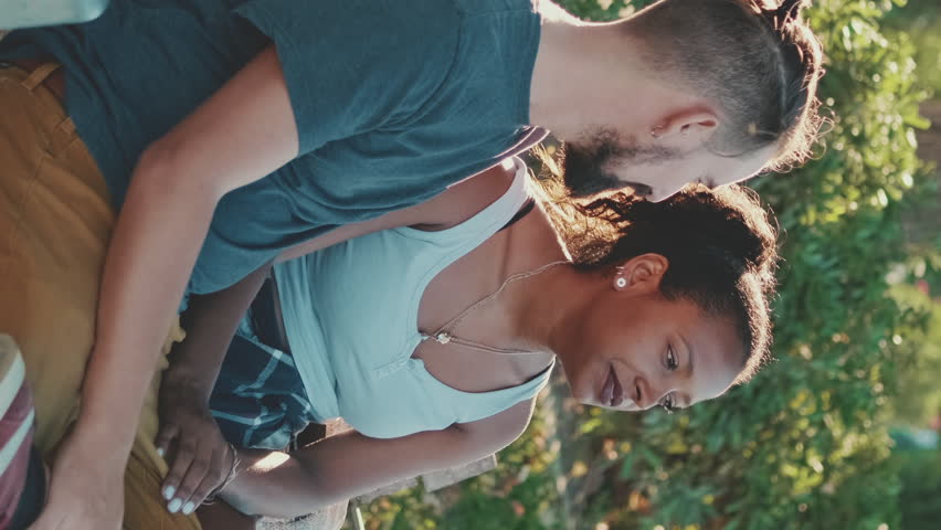 VERTICAL VIDEO, couple talking while sitting on bench. Backlight | Shutterstock HD Video #1099959647