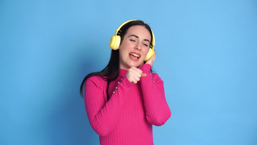 Smiling woman listening to music in headphones and singing