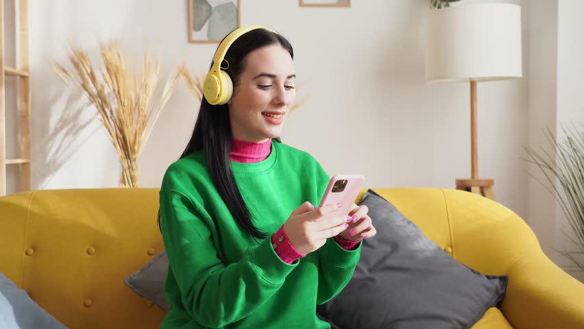 Cheerful woman with headphones using smartphone listening to music | Shutterstock HD Video #1099962417