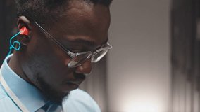 Closeup of young Black man in eyeglasses working with mainframes in server room of data center - Powered by Shutterstock - Get 15% off with code: PIKWIZARD15