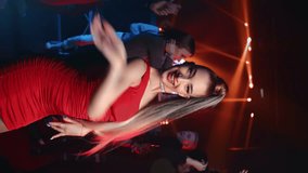 VERTICAL VIDEO POV fashion blonde woman dancer choreography performance at nightclub party. Smiling glamour female in red dress dancing dynamic energy movement posing enjoy nightlife discotheque 