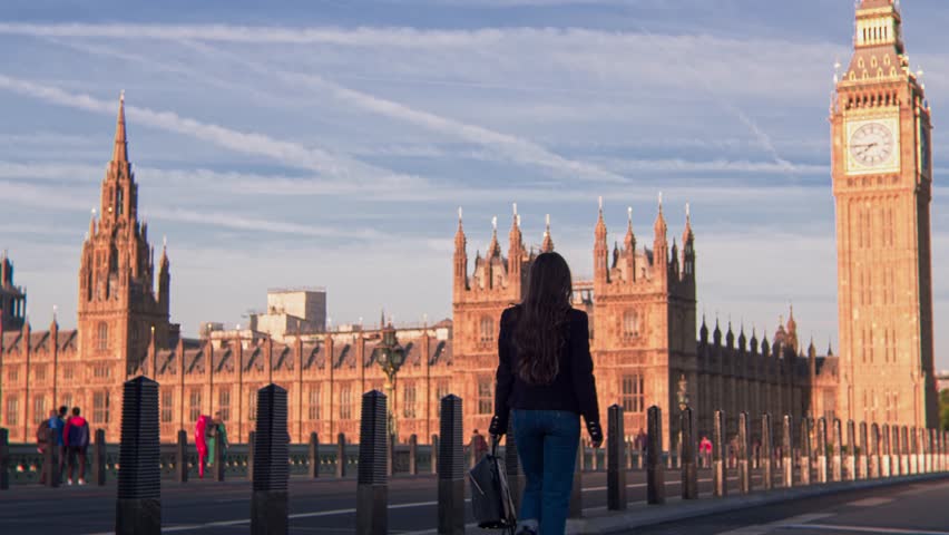 Tracking shot of young woman walking on Westminster Bridge London with Big Ben view. Stylish trendy tourist woman having a walk on Westminster Bridge on a morning sunny day Royalty-Free Stock Footage #1099965903