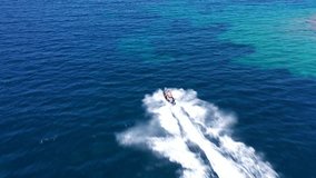 Aerial drone video of high speed jet ski water craft cruising in tropical exotic island bay with deep blue sea