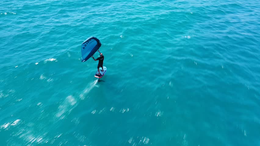 Aerial drone video of fit athlete practise hydro foil wing surfing in tropical exotic bay Royalty-Free Stock Footage #1099965993