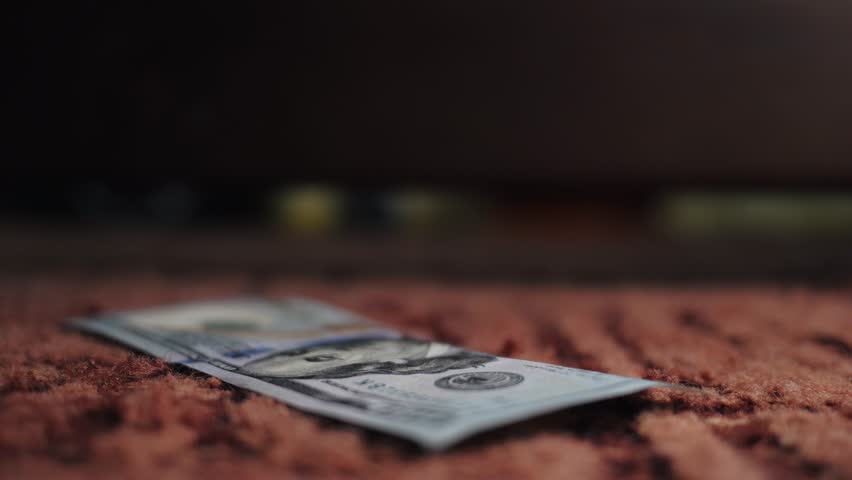 A man searches under his bed for a lost $100 bill. A man's hand takes out money lying under furniture in a hard-to-reach place. Royalty-Free Stock Footage #1099968281