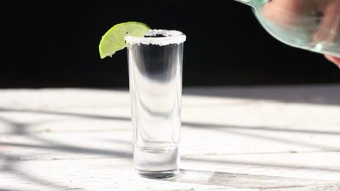 Стоковое видео: close up slow motion of bottle serving shot of tequila, mezcal