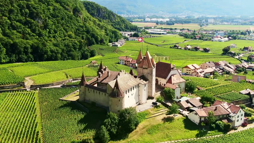 Drone Switzerland 4k. Swiss flag on castle Chateau Aigle. Wine region, vineyard fields and Swiss Alps. Popular wine tour destination in summer. 