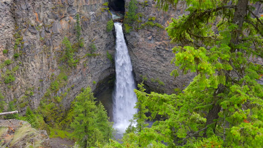 Establishing shot of majestic mountain waterfall with mountain background in Vancouver, Canada, North America. Day time on July 2022. Still camera view. ProRes 422 HQ.
