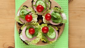 Top view of appetizing sandwiches with sausage and vegetables on a wooden board. Healthy hearty breakfast. Tasty organic food. Meal background. Flat lay, close-up, mock up. Video with rotation
