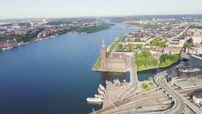Inscription on video. Stockholm, Sweden. Stockholm City Hall. Stockholms stadshus. Built in 1923, red brick town hall. Shimmers in colors purple, Aerial View, Departure of the camera