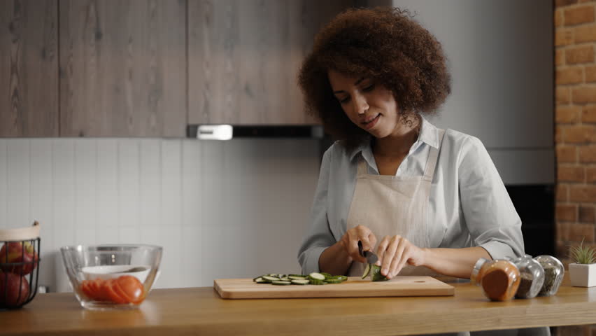 Young woman cooking dinner, boyfriend joining her in the kitchen, relationship | Shutterstock HD Video #1099980887