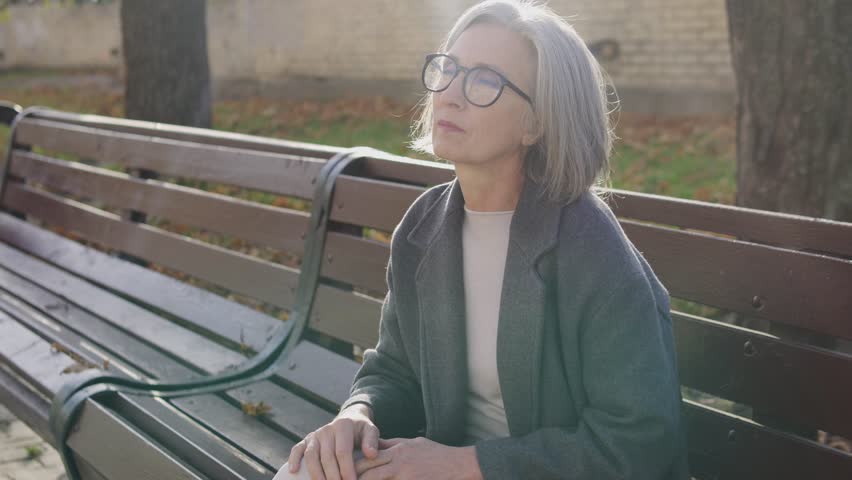 Nervous woman sitting on bench and holding hand on chest, feeling acute pain in heart and cardiopalmus, risk of heart attack or angina, emergency situation, call 911 Royalty-Free Stock Footage #1099982113