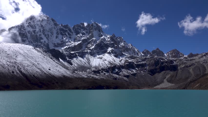 Gokyo lake with snowy Himalayan mountains, 2023 
boulder and cairns in the water, slow motion, himalaya, Everest National Park, Nepal, 2023,
