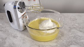 Time lapse. Close up view. Mixing ingredients in a glass mixing bowl to bake funfettti bundt cake.